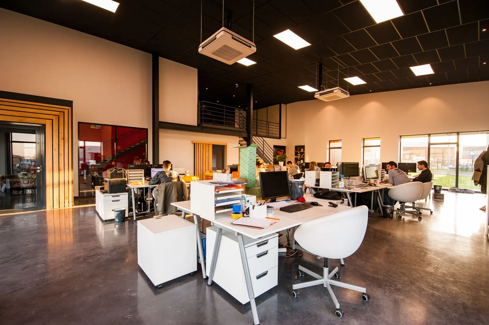 Bright open-plan office with daylight, desks, and glass walls