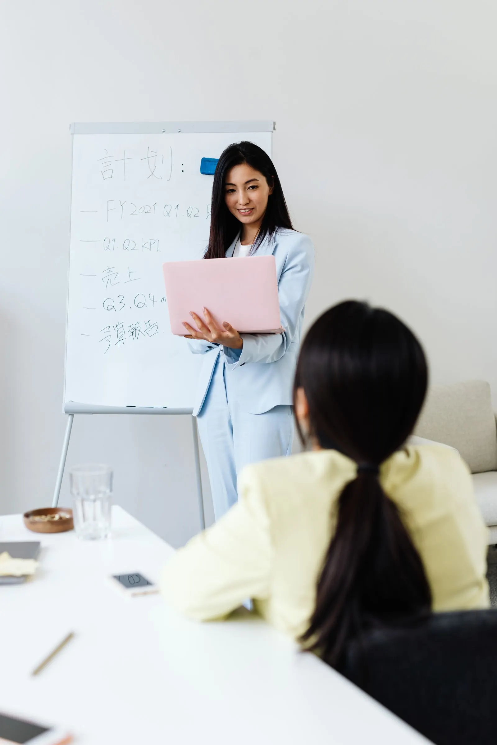 Two people standing beside a whiteboard and laptops during a planning session